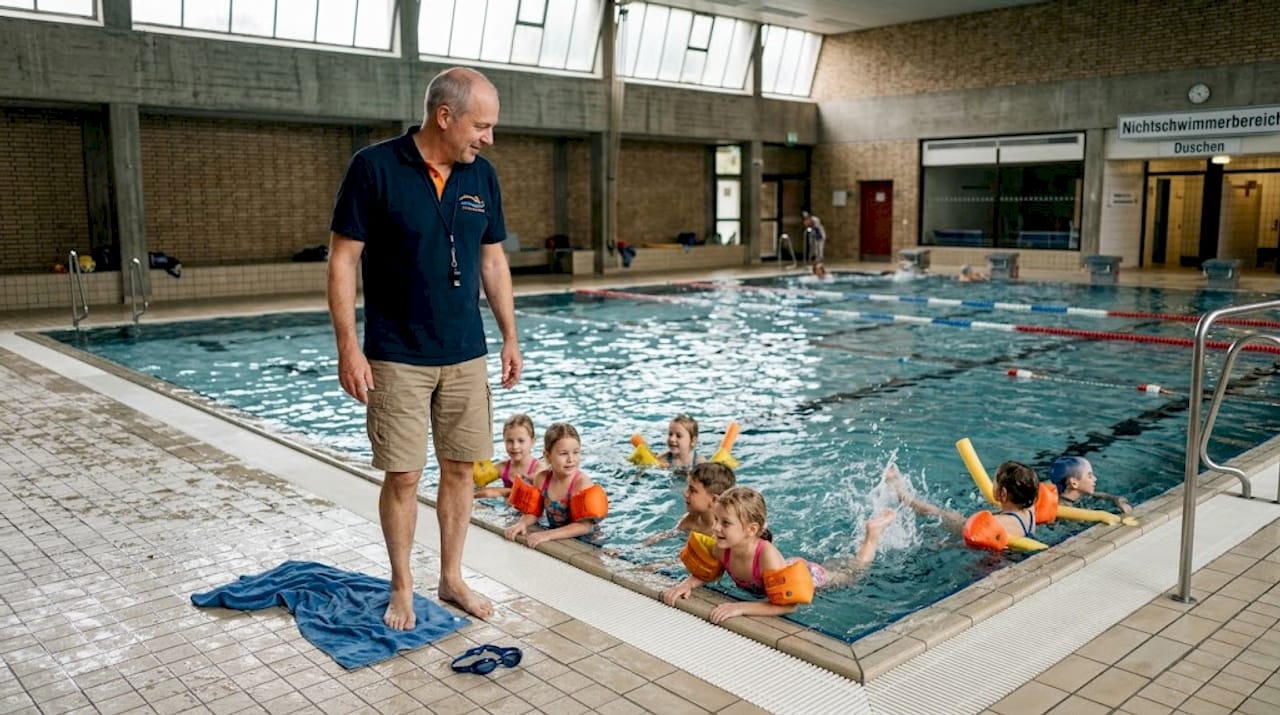Der Schwimmlehrer passt während des Unterrichts aufmerksam auf die Kinder auf.