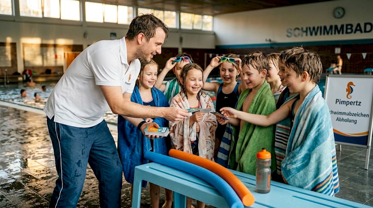 Die Trainerin verteilt am Beckenrand Motivationskarten an die Schwimmer.