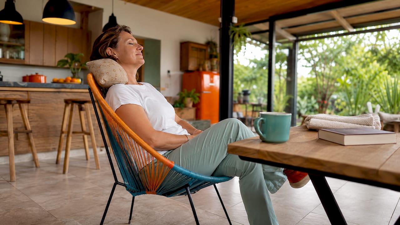 Eine Frau entspannt sich auf dem Sofa und genießt die wohltuende Wärme eines Kirschkernkissens.