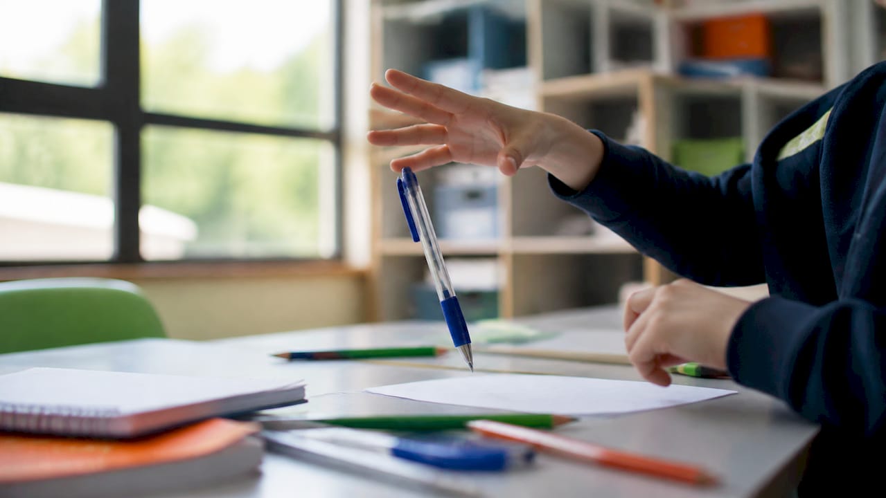 Jemand legt den Stift achtlos auf den Schreibtisch.