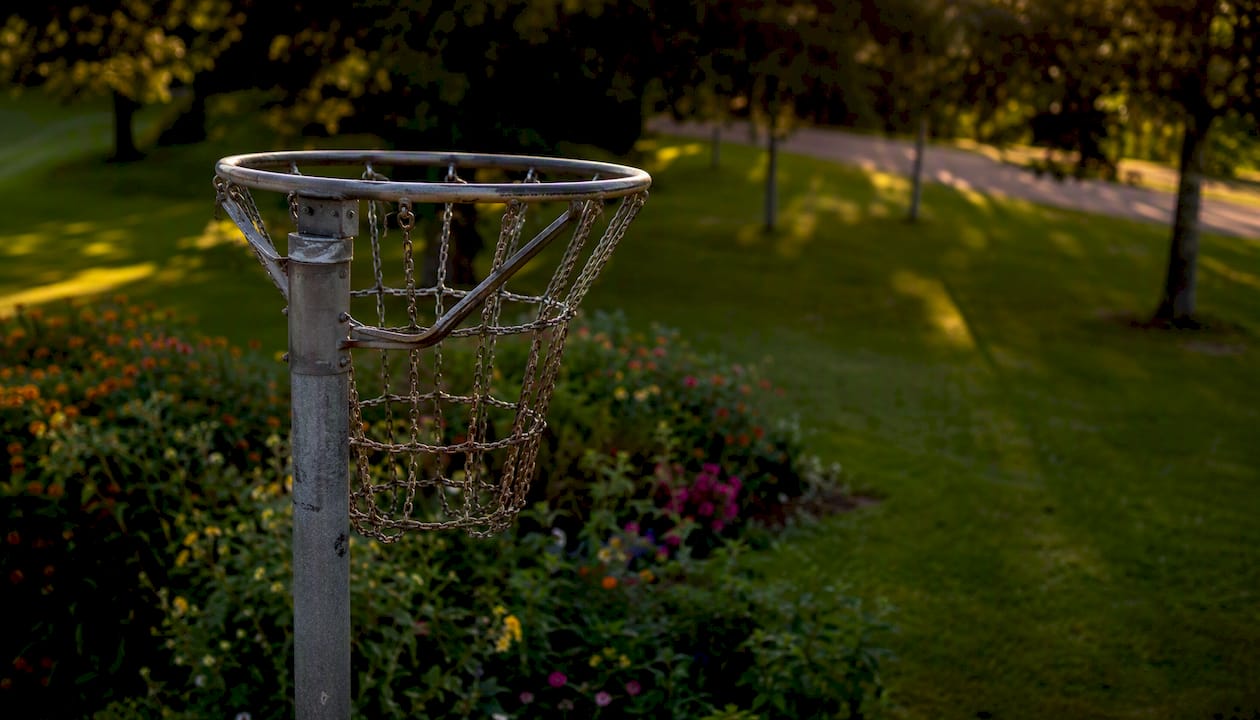 Draußen angebrachter Basketballkorb mit stabilem Metallpfosten und Netz.