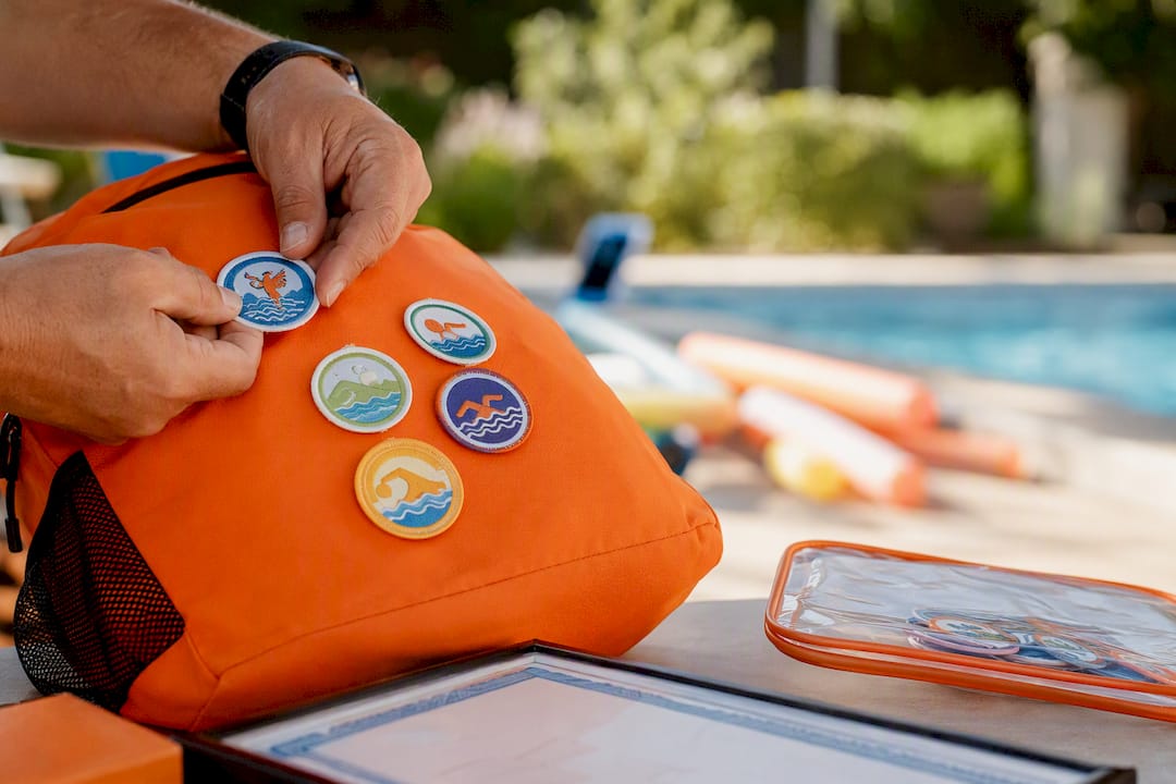 Hände, die Schwimmabzeichen an einer Sporttasche befestigen