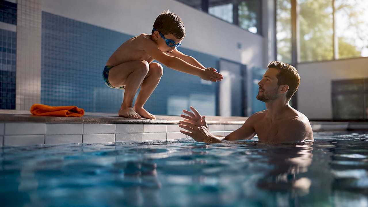 Kind übt Sprung für die Schwimmprüfung im Becken