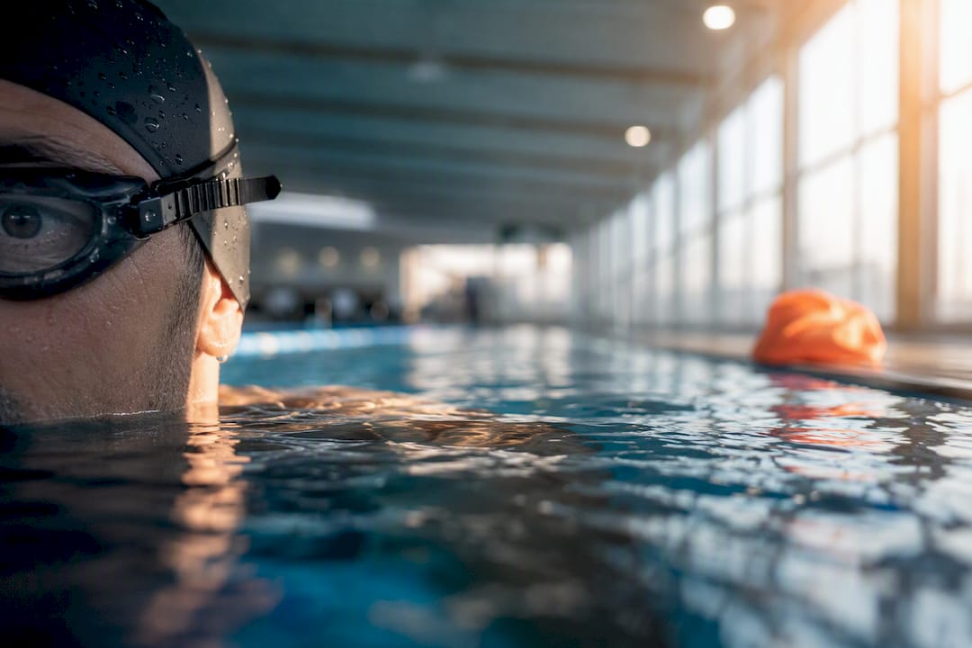 Schwimmer mit undurchsichtiger Schwimmbrille im Hallenbad