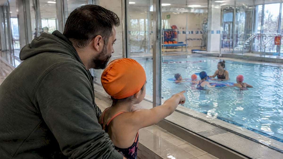 Eltern schauen beim Schwimmkurs im Hallenbad zu